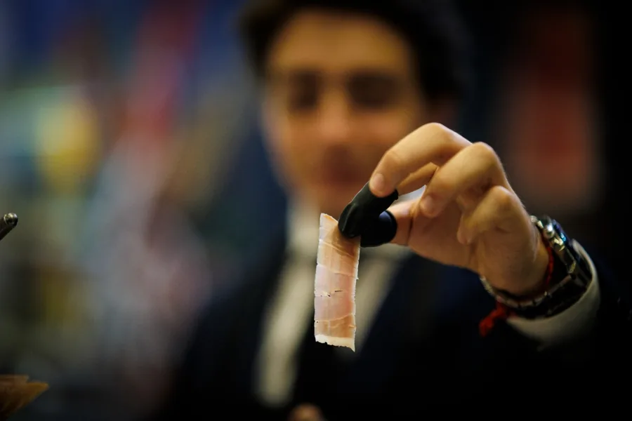 El cortador muestra una loncha de jamón para apreciar su aspecto y textura